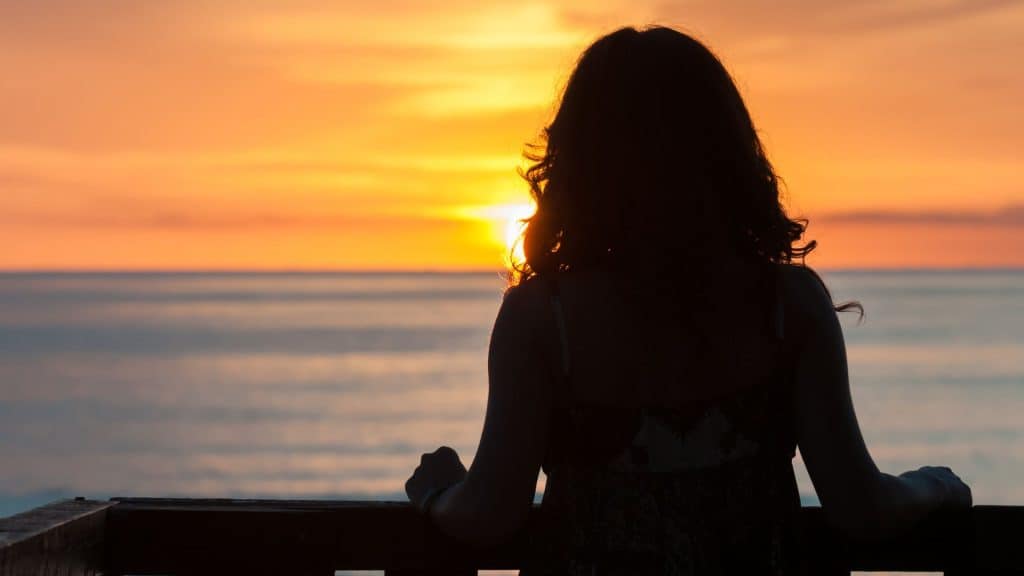 Silhouette of woman watching the sun rise on a new day.