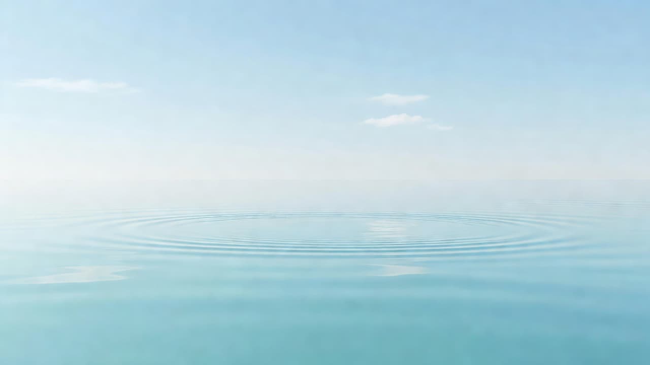 A tranquil pond surface occupies the frame, displaying gentle ripples that distort the reflection of a soft blue sky. The minimalist composition features airy light tones to evoke pure serenity.